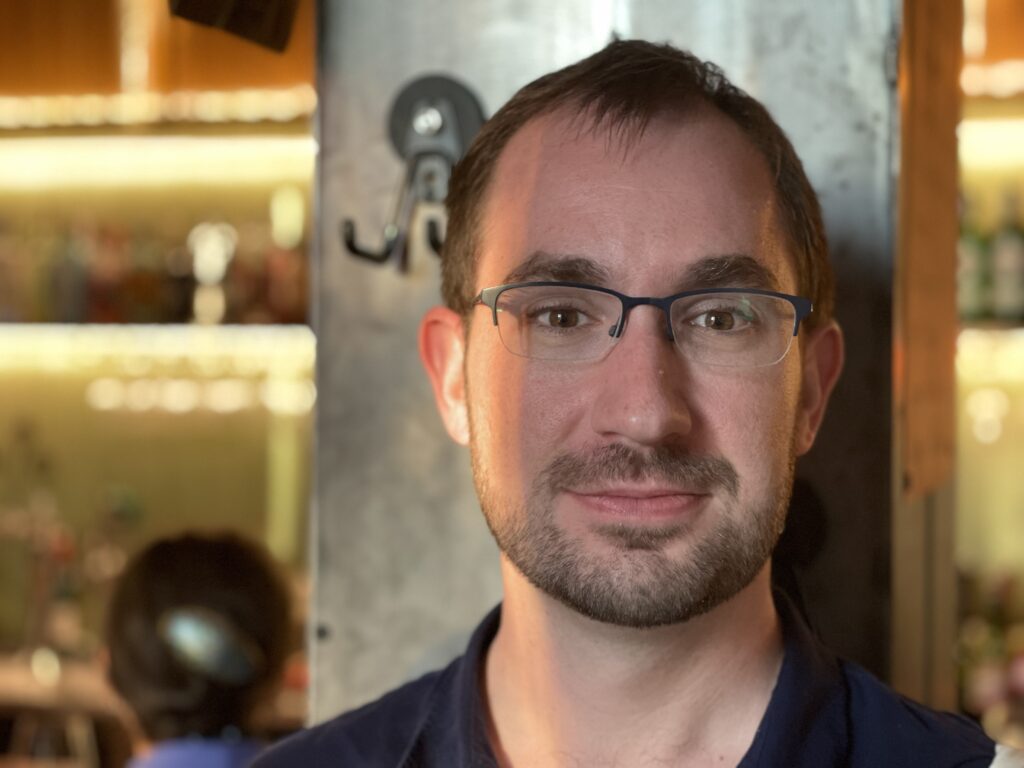 Photo of a late-20s white man with short brown hair and a short beard, looking directly at the camera.